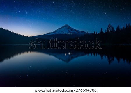 Stars in the night sky and Mount Hood reflecting in Trillium Lake at night, in Mount Hood National Forest, Oregon.