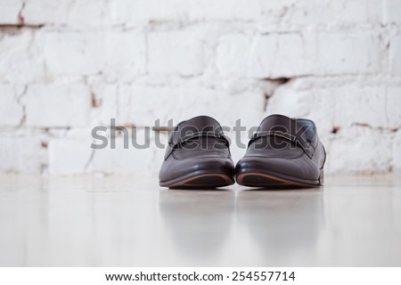 Pair of black elegant male shoes on white floor