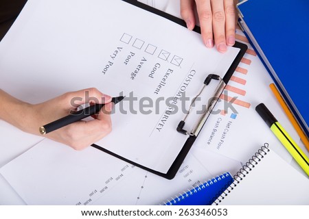 Human hands with pen filling customer survey blank
