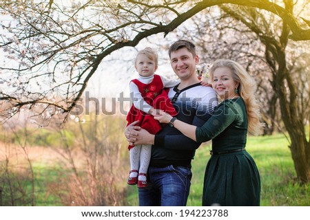 Family walk in the spring garden; mother, father and little daughter