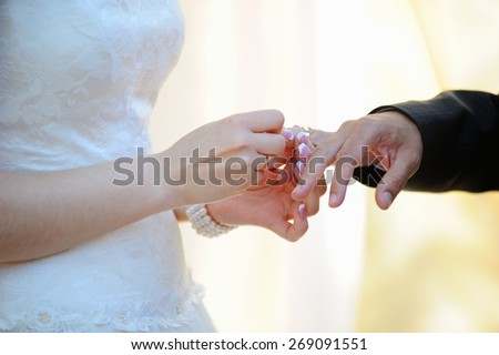 Bride putting a wedding ring on a groom\'s finger