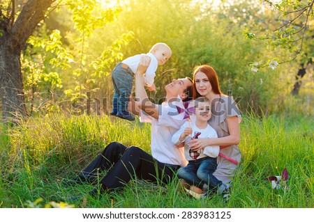 Father, mother and two sons are playing in the garden on sunset