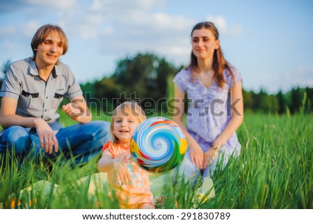 Mother, father and daughter play ball outside