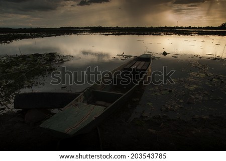 Storm clouds over water landscape old wooden fishing canoe