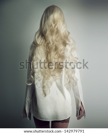 Girl with white hair in a white shirt stands with his back