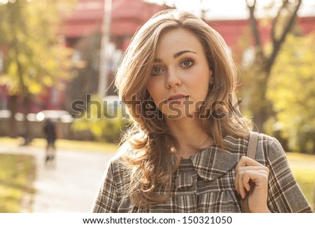 beautiful young woman outside in autumn city park dressed in casual