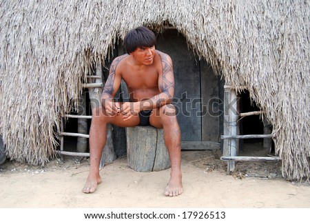 KAMAYURA VILLAGE, BRAZIL - MAY 18: The Kamayura is a threatened Indian tribe of under 400 people. A man sitting at doorway of a hut on May 18, 2008, in Kamayura village.