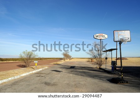 Sign for an abandoned motel on a desert road in rural Texas, with basketball court