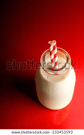 Vintage Milk Bottle with Stripy Straws on a Red Background