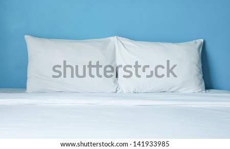 The couple white pillow on white bed in bright blue room