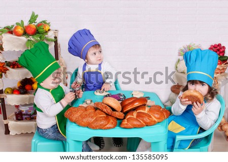 Funny children cooking in kitchen. small cute children in costume of Cook. Pretty beautiful children covered in flour makes cakes.