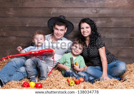 Happy family with children  - beautiful mother and father hug their sons, posing on hay  in studio closeup