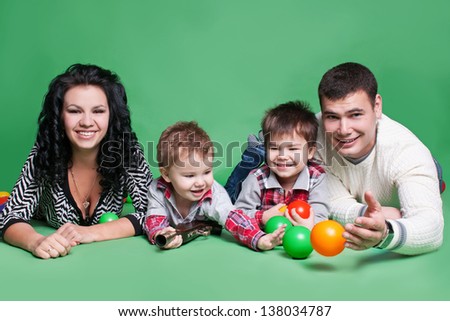 Happy family with children  - beautiful mother and father hug their sons, posing on green background in studio closeup
