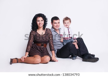Happy family with child - beautiful mother and father hug their son, posing on white background in studio closeup