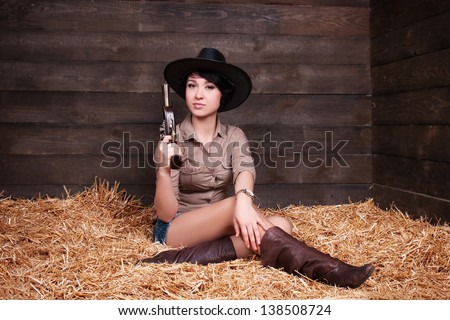 Fashion beautiful sexy cowgirl in jeans shorts and a shirt at the ranch farm. pinup and wild west western style. happy smiling slim girl on hay at farm. Fashion and pinup romantic american style.