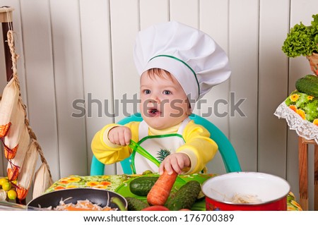 adorable baby cooking in kitchen. little cute child in costume of Cook. funny child makes a dinner.baby boy