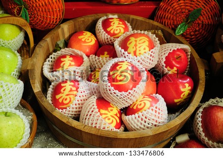 Words wishing luck and long life on red apples at a fruit stall at Chinese New Year
