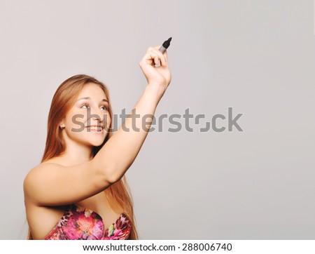 Attractive young woman writing with marker, isolated over plain background. Copyspace.
