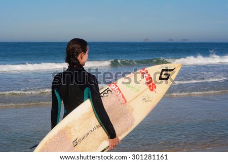 RIO DE JANEIRO, BRAZIL - JUNE 26, 2015: Woman surfing in a tropical beach on a sunny day in Rio de Janeiro.