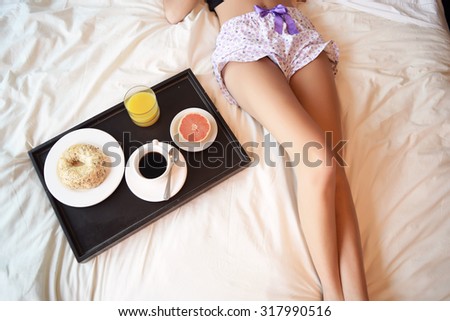 Young beautiful woman lying in bed with a breakfast tray. Soft picture.
