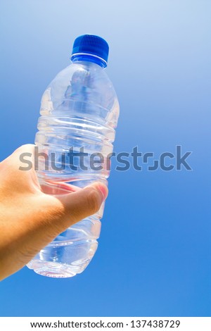 Hand holding a pet bottle isolated on a blue background of sky