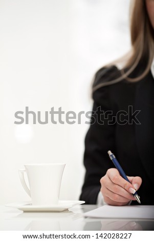 Closeup image of a businesswoman signing on a document with a pen in her hand, isolated on white background.