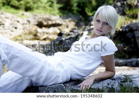 Model leans back on flat rock formation and poses for the camera