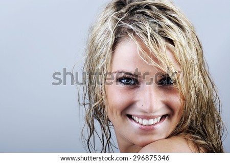 Close up Happy Attractive Young Woman with Wet Blond Hair, Looking at the Camera with Toothy Smile Against Gray Background with Copy Space.
