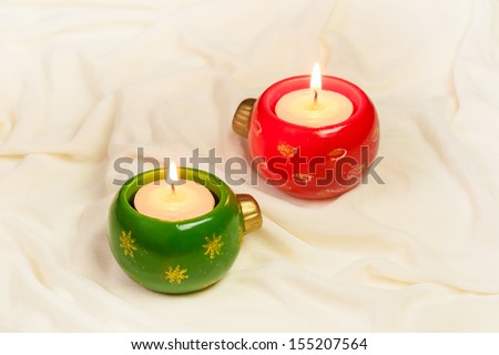 Advent Candles and Christmas - A pair of Christmas ornament shaped advent candles set on a cream colored silk cloth. Can be used as a background or in Christmas cards.