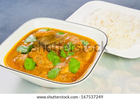 Indian Chicken Curry with Rice - Closeup view of delicious Indian chicken curry served with rice. The curry is prepared using onions, tomatoes, turmeric, garlic, ginger, cayenne and black pepper.