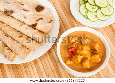 Folded homemade wheat chapati (Indian bread) served with delicious Indian paneer butter masala and cucumber salad. It is prepared using paneer (cottage cheese), butter, tomato and various spices.