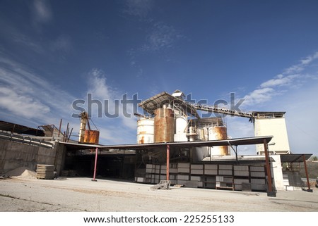 View of a white rusty old factory on a sunny sky.  Old withe factory.