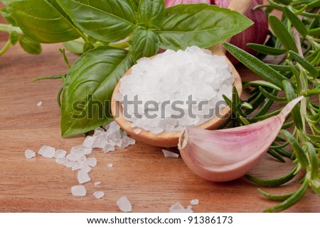 Fresh herbs and salt spoon on vintage wooden background. Shallow focus.