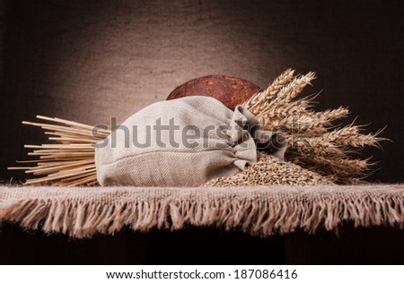 Bread, flour sack and ears bunch still life on rustic background