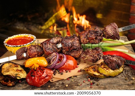 Shashlik or shish kebab prepared on barbecue grill over hot charcoal with grilled vegetables. Grilled pieces of pork meat on metal skewers.