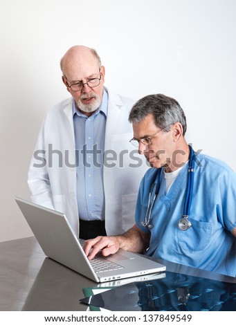 Medical doctors at laptop computer discussing patient\'s scans.