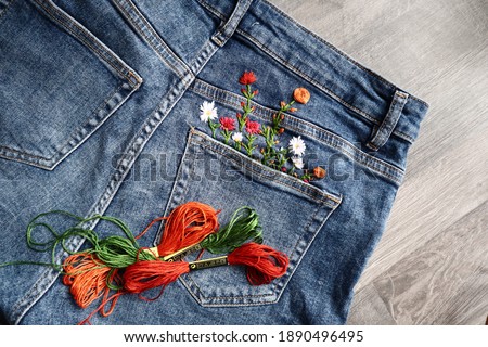 Creative DIY project, hand embroidery at home on jeans, creative hobby, clothes recycle, floral embroidery design, colorful threads, embroidery needle