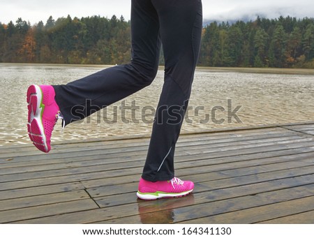 Sporty female running by the brown river Drava