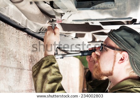 Mechanic Under Car Installing Exhaust Pipe