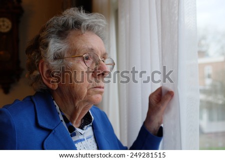 Elderly woman looks out a window