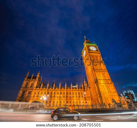 Black car under Big Ben and Houses of Parliament at night.