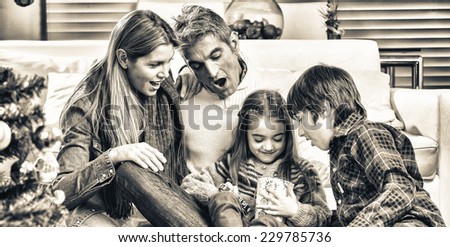 Christmas family scene. Daughter opening gift with parents and brother surprise.
