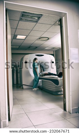 Computed tomography scan with male patient and female doctor. View from outside hospital room.