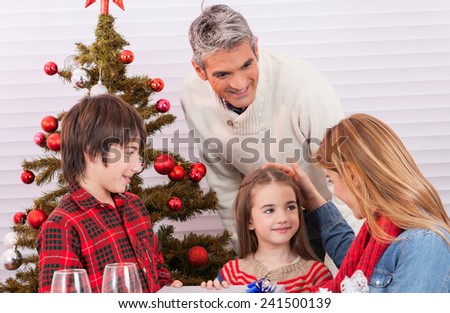 Happy family near the tree unwrapping Christmas gifts.