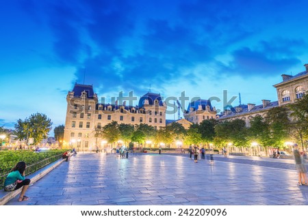 PARIS - JUNE 21, 2014: Tourists enjoy summer night lights in the square of Notre Dame. More than 30 million people visit the city every year.