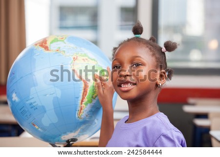 Young afro american black girl at school smiling touching a world globe.