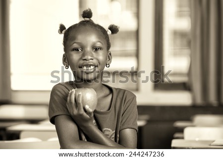 Afro american girl at elementary school holding a green apple.