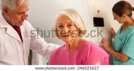 Senior male doctor and female assistant examining woman in 70s with CT scanner. Computerised tomography.