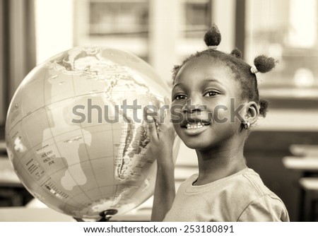 Young afro american black girl at school smiling touching a world globe.