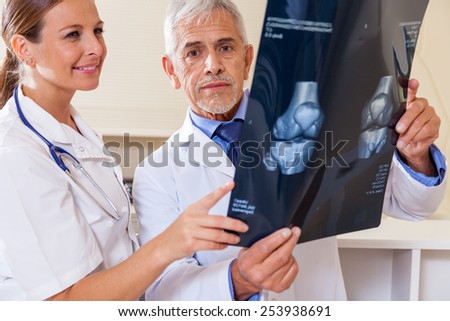 Expert doctor analyzing x-ray scan with female assistant.